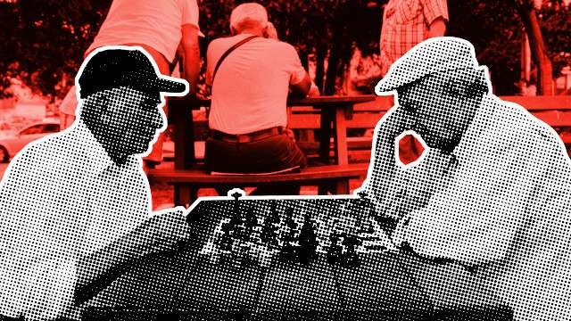 Two old men playing chess at a table in a a park